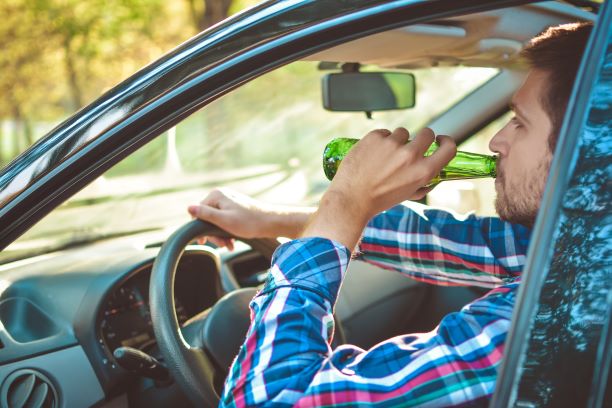 Butte County CA. Drunk teen man driving a car as soon as a bottle of beer. Don't drink and drive. Driving under the influence. DUI, DWI, Driving while intoxicated