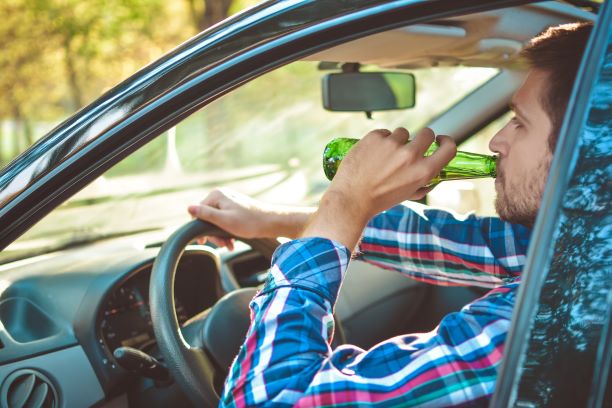 Nevada County CA. Drunk young person man driving a car in imitation of a bottle of beer. Don't drink and drive. Driving below the influence. DUI, DWI, Driving though intoxicated